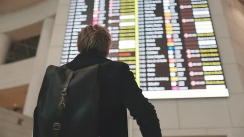 Traveler Checking Flight Information Board at Airport