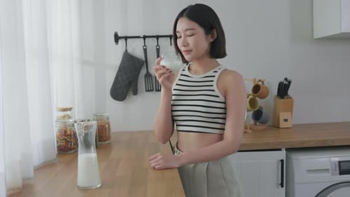Young Woman Enjoying a Glass of Milk in Kitchen