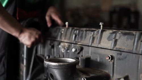 Mechanic repairs and assembles engine in dark garage