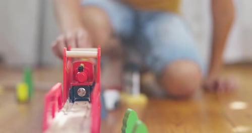 Child Pushes Wooden Train on Tracks