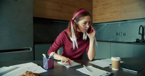 Young Woman Talking on Phone and Taking Notes