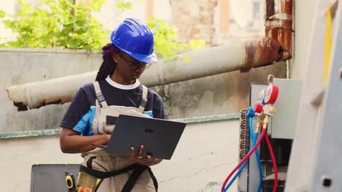 Woman in Hardhat Uses Laptop Repairing AC Unit