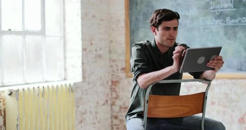 Jeune homme adulte utilisant une tablette numérique dans un bureau créatif