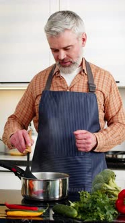 Man Cooking Vegetables in Kitchen with Apron