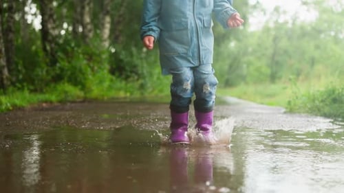 Little Child Jumps in Puddle on Park Road