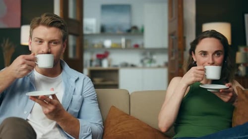 Couple drinks coffee together at home on couch