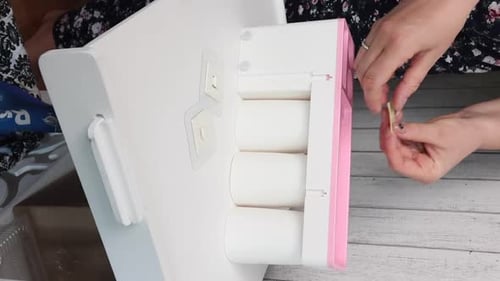 Une femme donne un aperçu d'un distributeur mural pour dentifrice avec un support pour brosses à dents