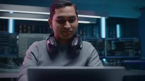 Young Man Works on Laptop in Tech Office