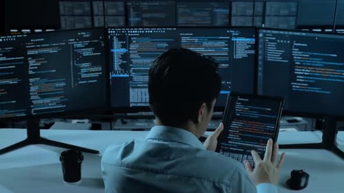 Asian Man Working With Tablet While Write Code With Multiple Computer Screens In office
