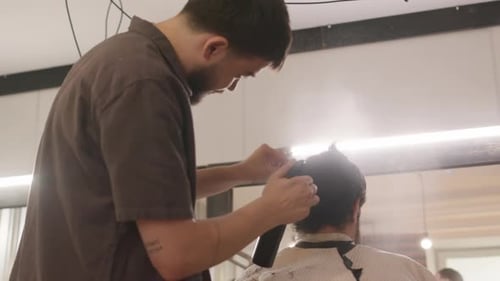 Hairstylist Cutting Man's Hair in a Barbershop