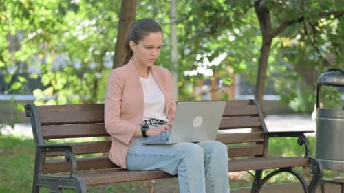 Woman Using Laptop on Park Bench Outdoors