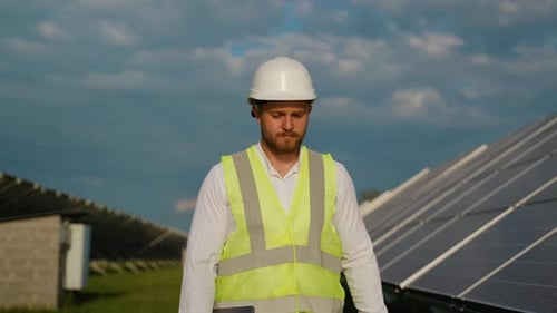 Solar Farm Engineer Walking and Inspecting Panels