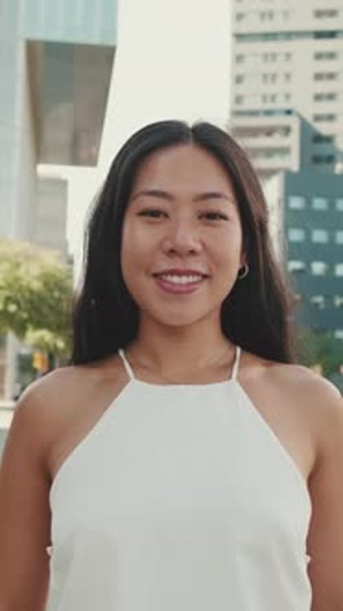 Beautiful smiling young woman looking at camera on modern city background