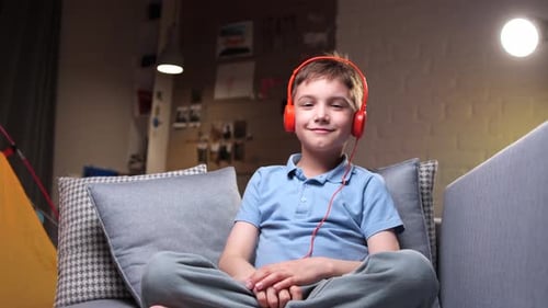 Child Smiles Wearing Headphones on a Couch