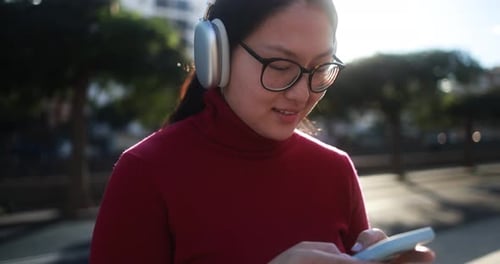 Young Woman Using Phone on Sunny City Street