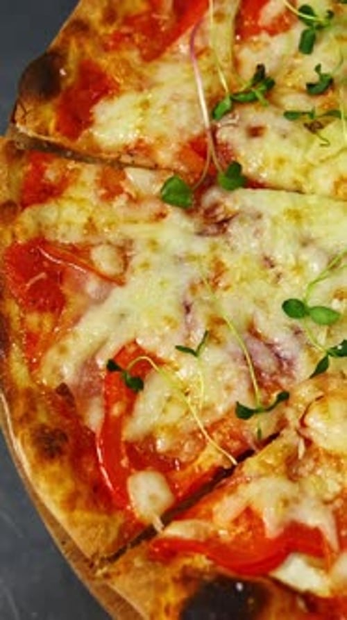 Delicious pizza. Ready pizza with melted cheese rotating on a table in pizzeria.