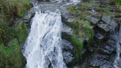 Ein wunderschöner Wasserfall in Zeitlupe, bei dem Wasser über die Felsen eines Flusses in ein Felsenbecken fließt