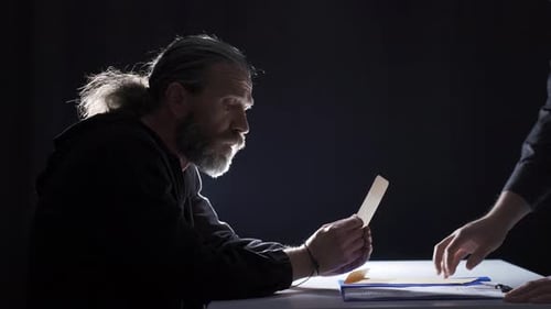 Man Reviewing Confidential Documents at Dark Table