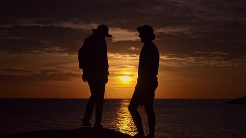 Two People are Standing Next to Each Other on a Beach at Sunset