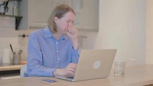 Woman Coughing While Using a Laptop at Home