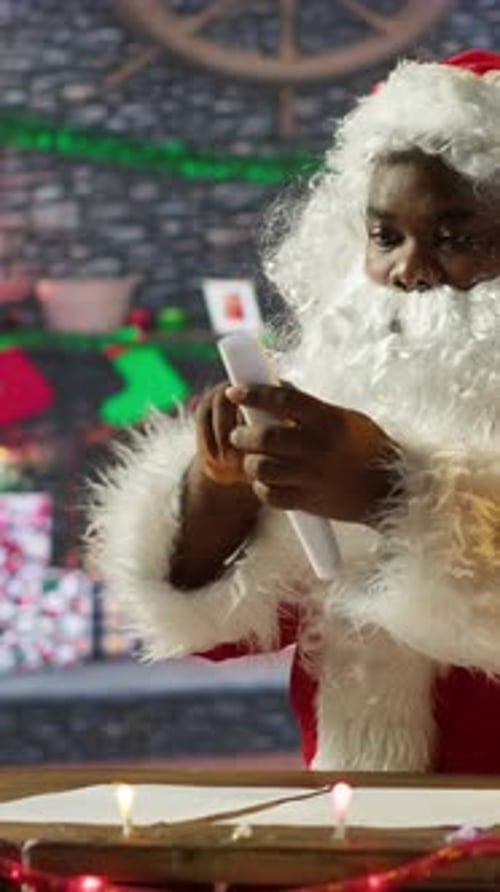 Santa Claus Reads Christmas List by Fireplace Indoors
