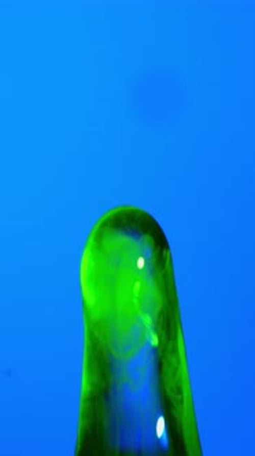 Green Water Droplet Splashing On Surface With Blue Background