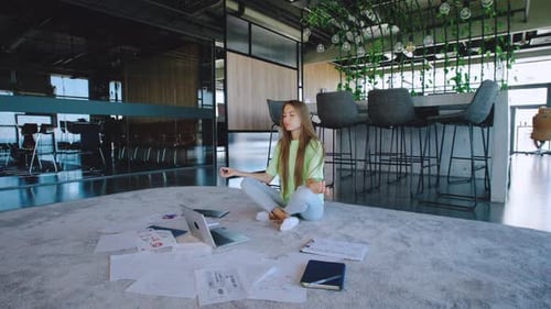 Young Woman Meditating in Modern Office Workplace
