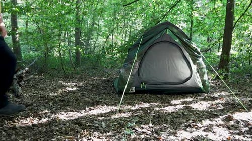 Tourist man adjusting the tent at a campsite in the woods. Slow motion