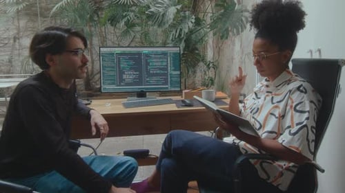 Female Programmer Making Notes and Talking with Coworker