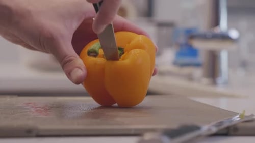 Hand Cuts Fresh Yellow Bell Pepper in Kitchen