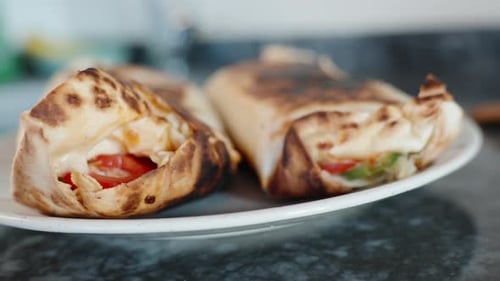 Cooking, Two fried shawarmas in the plate. Close-up in motion. Black stone countertop.