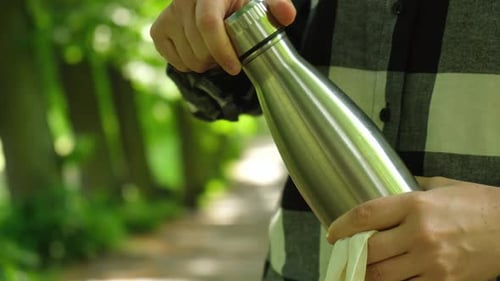 Primer plano de una irreconocible mano femenina que sostiene una botella de agua de Eco Bag