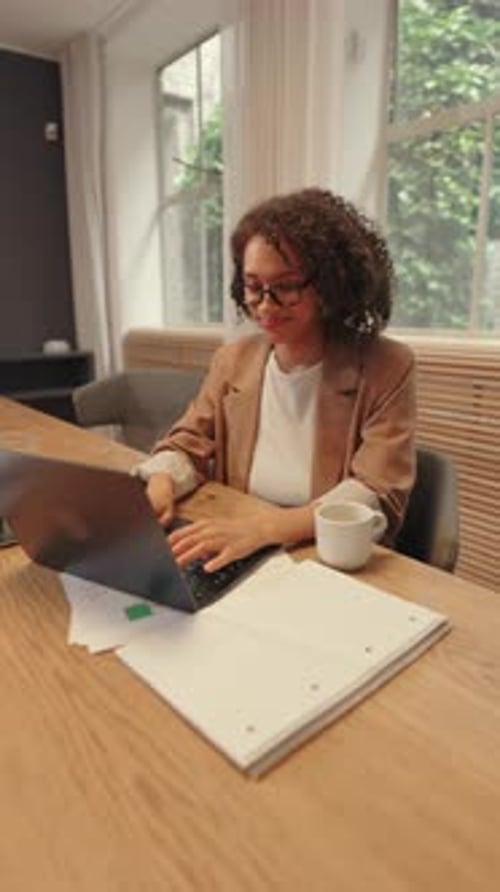 Focused Business Woman Working on Laptop at Modern Office Desk with Documents