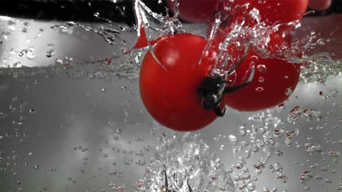 Bright Red Tomatoes Plunge into Refreshing Water