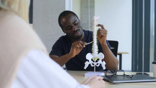 Man is showing spine model, problems with back.