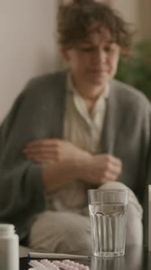 Woman Taking Pill with Water Indoors