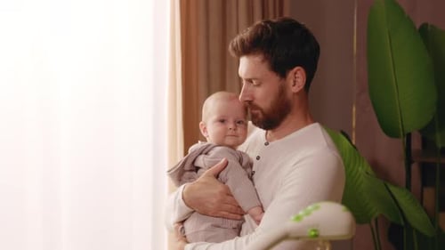 Loving Father Holds Newborn Baby at Home