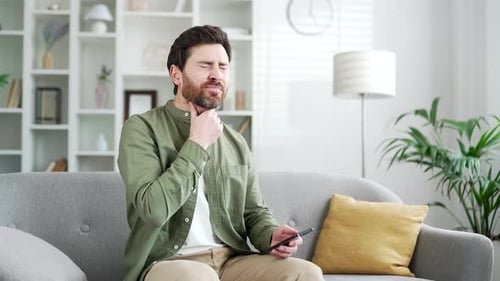 Man with Sore Throat Holds Mobile Device