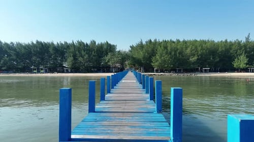 Scenic View of a Blue Pier Stretching into Calm Water Under Sunny Sky