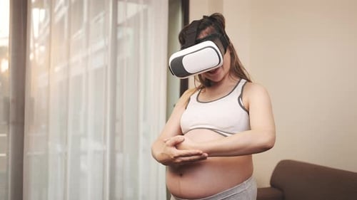 Pregnant Woman Wearing VR Headset Touching Stomach
