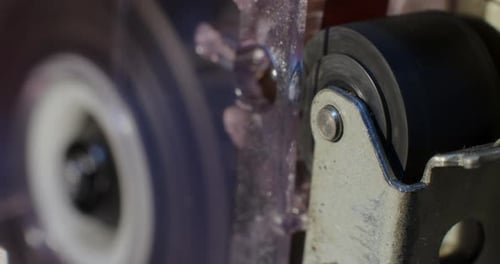 Extreme Close-Up Of Pinch Roller Of Microcassette Recorder With Cassette Reel Rotating in Background