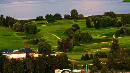 Lush Green Golf Course by Lakeshore with Fairways and Bunkers at Sunset