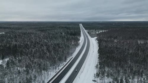 Atemberaubende Luftaufnahmen einer ruhigen Winterautobahn über einer wunderschönen schneebedeckten Landschaft für