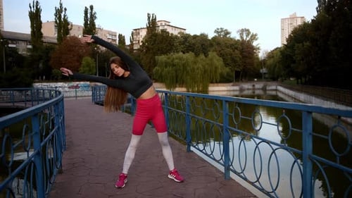 Outdoor Fitness Routine in Urban Park Woman Stretching By the Water