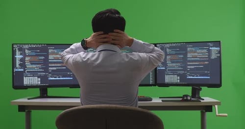 Back View Of Developer Having Headache While Write Code With Multiple Screens In Green Screen
