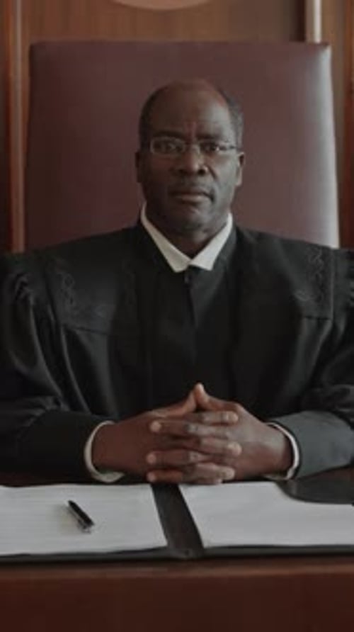 Judge Sits at Desk in Courtroom