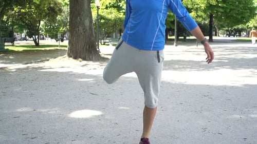 Young Man Stretching Legs Before Jogging in City Park, Super
