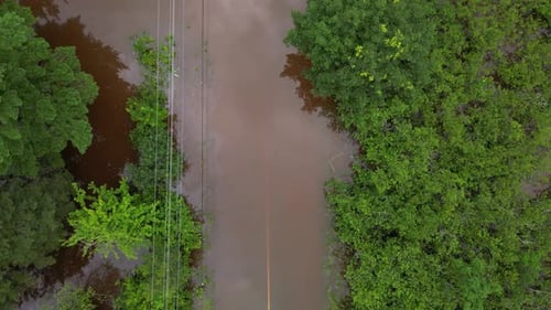 Top down flooded road submerged underwater due to river overflowing after extreme weather event