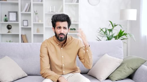 Man Feeling Overheated Fanning Himself on Sofa