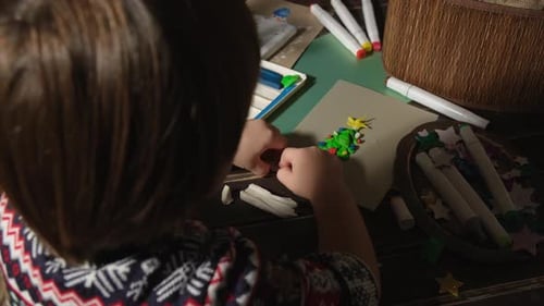 Small Boy Creating Christmas Greeting Card Using Plasticine and Coloured Paper